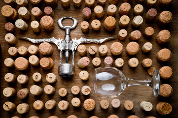 Wine corks of different sizes, a corkscrew, a bottle of wine and a glass shot on an old wooden...