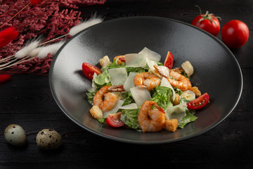 caesar salad with shrimp on a dark wooden background