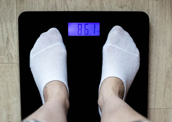 Women's feet on floor scales, top view. The weight display on the outdoor weights in pounds. The concept of weight gain/loss.