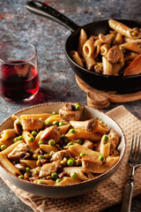 Homemade pasta with green peas, chicken and sauce on a dark background