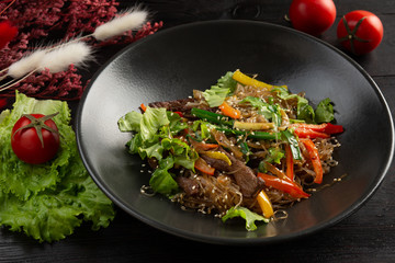 funchose noodles with veal on a dark wooden background