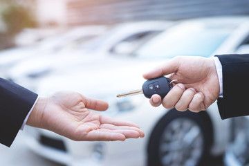 Car key, businessman handing exchange over give to the other man on showroom background. Seller dealer credit Interest payment or purchase by installment car concept.