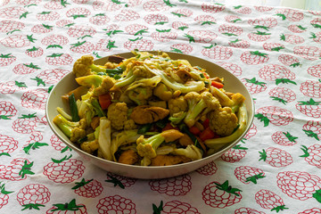 stir fry salad, asian style cooked. Salad with cauliflower, chicken, onion, broccoli and lettuce served on a plate