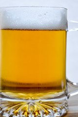 mug of fresh light beer on wood, back lit closeup
