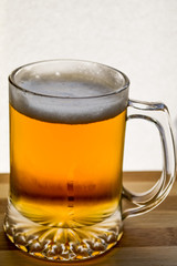 mug of fresh light beer on wood, back lit closeup
