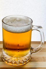mug of fresh light beer on wood, back lit closeup