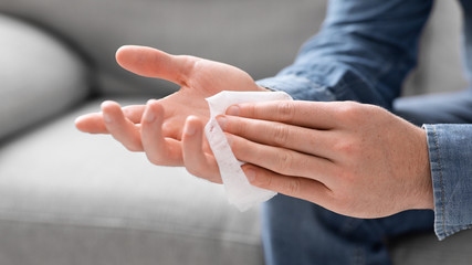 Man disinfecting palms with antibacterial napkins, close up