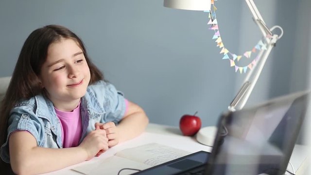 child student study online with video call teacher. Happy young girl look at laptop and wave his hands. stay at home. distance learning. communication via the Internet