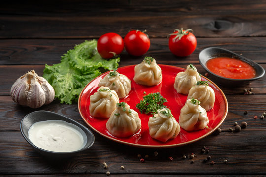 gedza with beef on a red plate and sauce in a cup