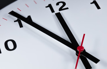 It is five to twelve, the clock is ticking. Modern white grey clock shows the time 5 before 12....