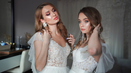 Two young models posing in front of the photographer in a wedding dress.