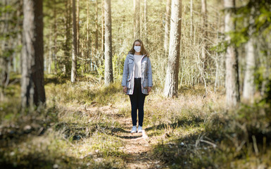Obraz premium Woman in medical mask in the middle of the forest.