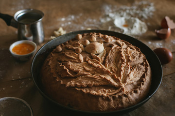 close-up of a richly baked homemade cake decorated with leaves and berries from the dough and...