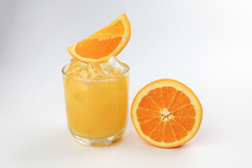 Fresh yellow orange juice in glass with orange slice and ice cube on white background