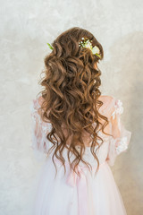 A girl with spinners demonstrates a wedding hairstyle.