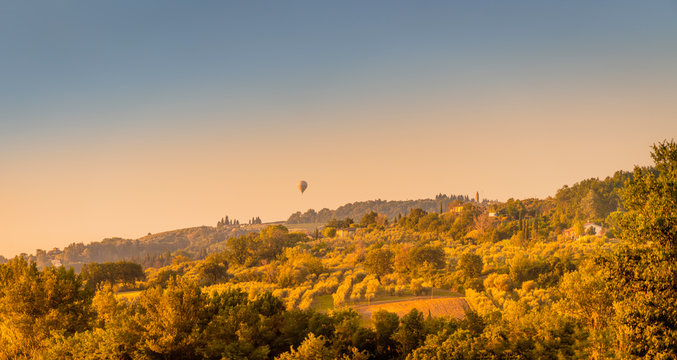 Summer sunrise over the fields and rolling hills with air balloon. Travel destination Chianti, Tuscany