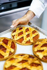 crostata appena pronta in vassoio tenuto in mano da pasticcere