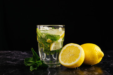 glass of mojito decorated with a sprig of mint and lemons on a dark background. close horizontal picture