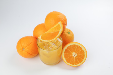 Fresh yellow orange juice in glass with whole sliced orange fruit and ice cube on white background