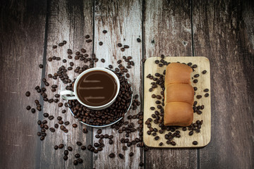 Hot coffee with bread on a wooden background, coffee mugs and coffee beans, hot coffee in the morning
