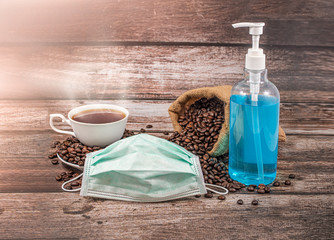 Mask and gel, alcohol, hand sanitizer with a cup of coffee placed on a wooden floor