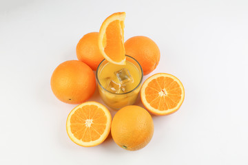 Fresh yellow orange juice in glass with whole floating sliced orange fruit and ice cube on white background