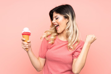 Teenager girl holding a cornet ice cream isolated on pink background celebrating a victory