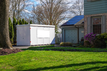 White storage pod unit in the driveway of a home that has solar panels