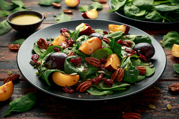 Vegan plums salad with cranberry, pumpkin seed, pecans nuts, spinach and mustard dressing