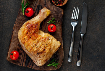 one grilled chicken leg with spices on a cutting board on a stone background