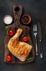 one grilled chicken leg with spices on a cutting board on a stone background