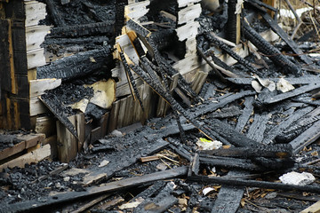 Wooden house after the fire. Coals on the logs. The ashes of the house from the fire. Burnt destroyed cottage.