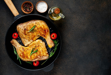 two grilled chicken legs with spices on a grill pan on a stone background with copy space for your text