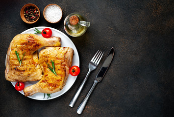 two grilled chicken legs with spices on a white plate on a stone background with copy space for your text