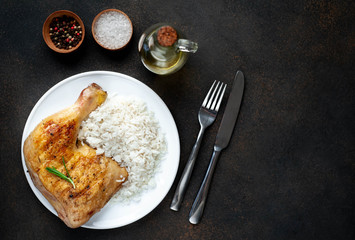 Grilled chicken leg with spices and rice on a white plate on a stone background with copy space for your text