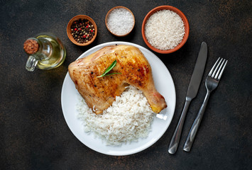 grilled chicken leg with spices and rice on a white plate on a stone background
