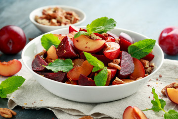 Vegan Plum, beet salad with pecan nuts, mint and herbs in white bowl. healthy summer food.