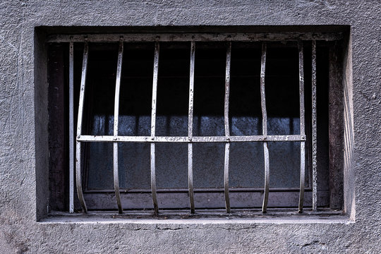 Dirty window with metal bars. Old wooden window with a metal grille. Basement window with a metal barrier. 