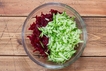 Step by step cooking of summer cold soup with beets and kefir, step 3 - adding grated fresh cucumber, top view, top view, selective focus