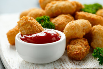 Crispy Battered scampi nuggets with ketchup on white wooden board