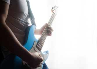 Medium shot of man playing a blue and white electric guitar