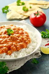 Spicy chickpeas curry with rice, tomato and Poppadoms in white plate. Healthy tasty vegetarian food