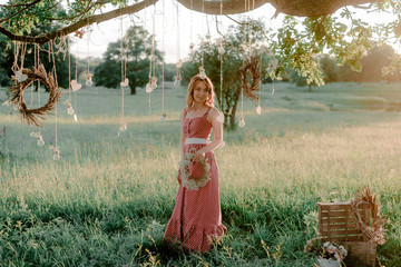 A beautiful young girl in nature in a rustic style in green grass, boho and rustic style, ...