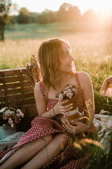 A beautiful young girl in nature in a rustic style in green grass, boho and rustic style, ...