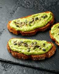 Healthy Homemade Avocado creamy Toast with nuts mix on rustic stone board