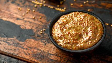 whole grain mustard in bowl on wooden table.