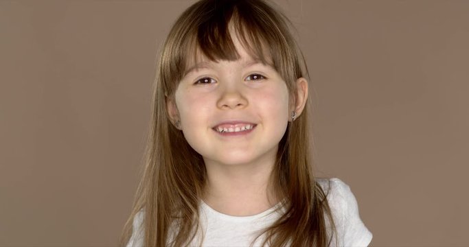 Portrait of a little cute 7 year old girl in a white tshirt, posing and smiling