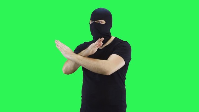 The masked man shows his hands with his feet.Balaclava.Green screen background.