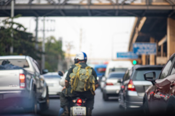 Blurry background of rear view of man driving motorcycle and may cars driving on road, Terrible traffic jam in city