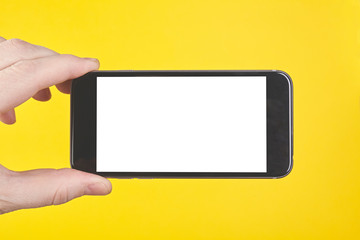 Hand hold smartphone on yellow background. Close up